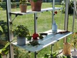 Diese Ansicht zeigt einen Gartentisch aus Aluminium mit zwei Regalböden darunter. Die zweifache Anordnung ermöglicht eine geordnete Aufbewahrung von Werkzeugen und anderen Gartengeräten.