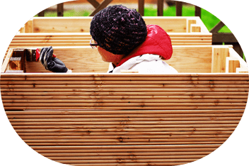 Person pflegt Hochbeet aus Holz